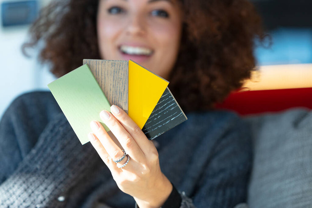 A close up of a young woman holding multiple paint colour or cladding samples. - Valokuva, kuva