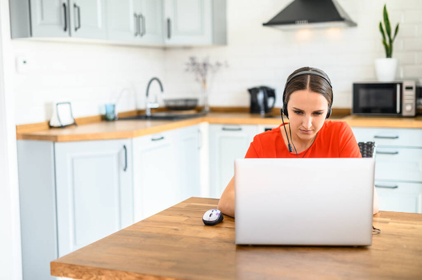 Young woman works from home using headset, laptop - Φωτογραφία, εικόνα