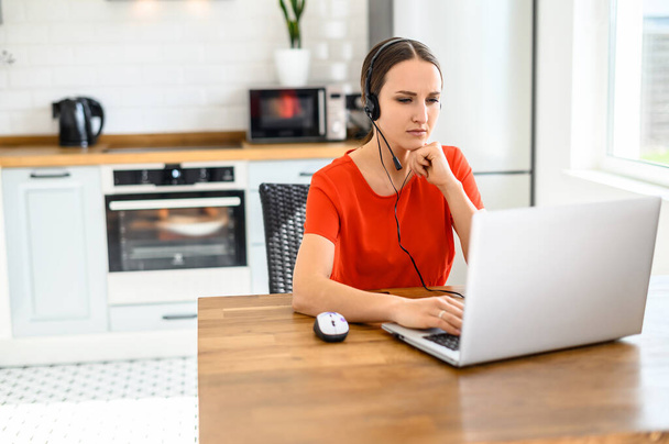 Young woman works from home using headset, laptop - Foto, Bild