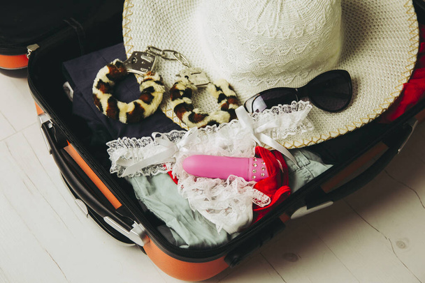 Traveling with sex toys concept. Packing sex toys in luggage suitcase when going on trip. - Foto, imagen