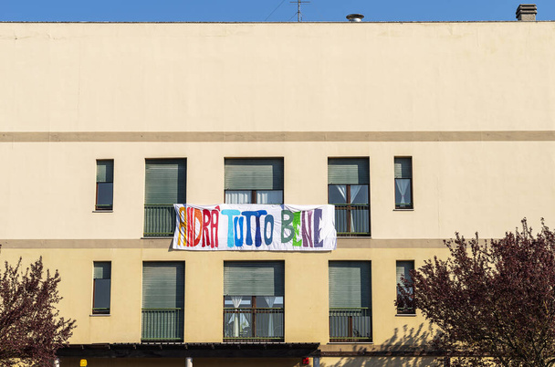 "andra' tutto bene"の旗のある家のファサード、コロナウイルス時代の希望のイタリア語のメッセージ - 写真・画像