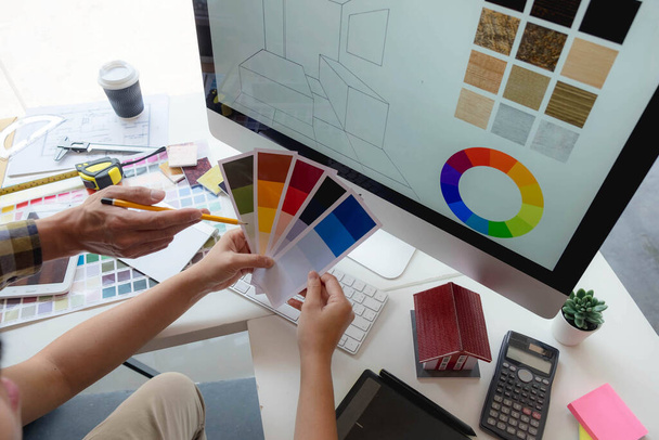 Mérnökök és kreatív művészek dolgoznak az asztalon, dolgoznak, konzultálnak, tanácsokat adnak a színek és anyagok kiválasztásához, mérik a méretet, hideg színeket, lágy tónusokat, gyönyörű tónusokat választanak. - Fotó, kép