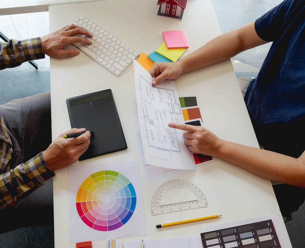 Ingenieure und kreative Künstler arbeiten am Tisch, arbeiten, beraten, beraten bei der Auswahl von Farben und Materialien, messen Größe, wählen kühle Farben, sanfte Töne, schöne Töne. - Foto, Bild