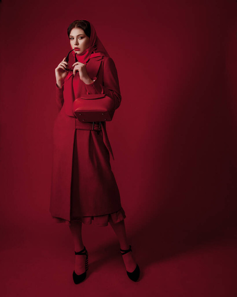 total red look. trendy fashion outfit. young beautiful woman posing in studio. Fashion concept. Lady with red lips looking at camera. cute red trench coat and kerchief. spring fashion concept - Photo, Image