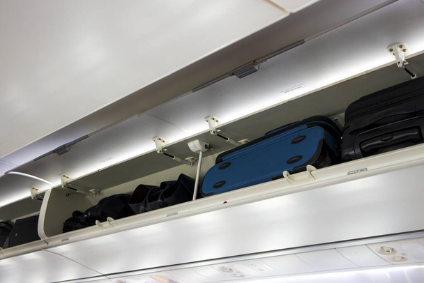 Carry on luggage bags in passenger airplane shelves closet, doors opened. Safety on plane concept. - Photo, Image