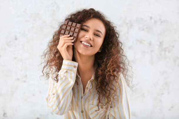 Jovem afro-americana com chocolate no fundo claro
 - Foto, Imagem