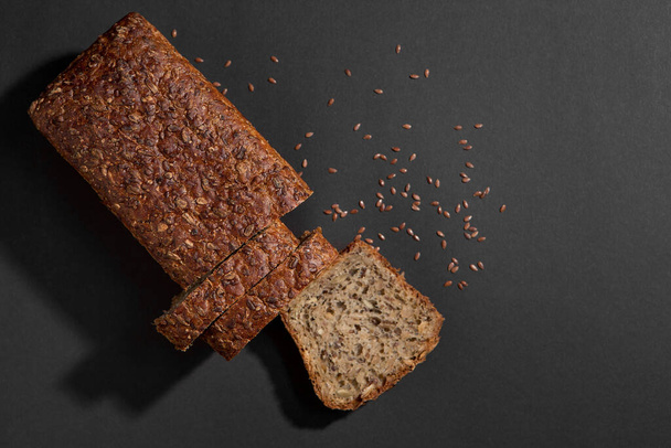 lahodné čerstvé pečené plátky chleba se semeny na tmavém pozadí, pohled shora, kopírovat prostor - Fotografie, Obrázek