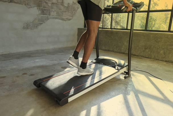Young man in sportswear running on treadmill at gym - Фото, изображение