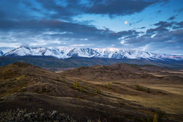 Morning in the Kurai steppe, the Moon over the North Chuysky ridge. Kosh-Agachsky District, Altai Republic, Russia - Фото, изображение