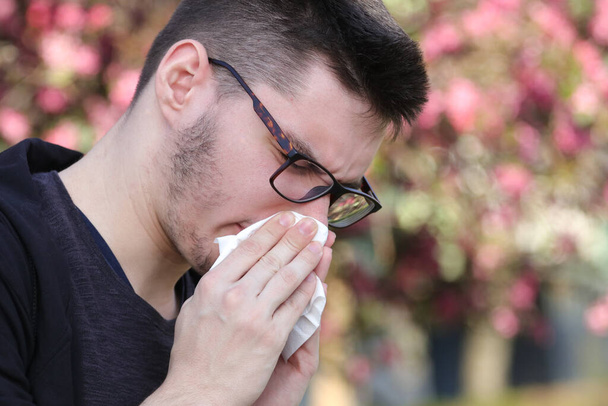 Sintoma de Covid-19, o jovem tosse em papel de tecido
 - Foto, Imagem