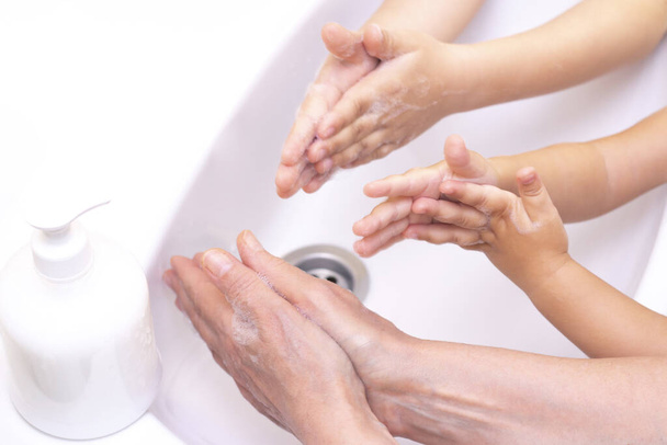 adults and children wash their hands. hands in foam from antibacterial soap. Protection against bacteria, coronavirus. hand hygiene. washing hands with water. many hands - Фото, изображение
