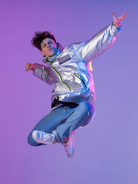 Cool guy dancing contemporary dance in studio. Neon light background. Acrobatic bboy dancer. Break dance lessons. - Photo, image