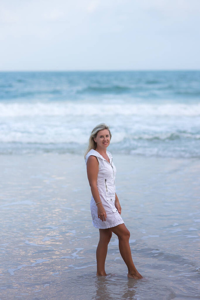 Portrait of woman walking on the beach looking at the sea. Relaxed lady strolling on the beach. - Foto, imagen