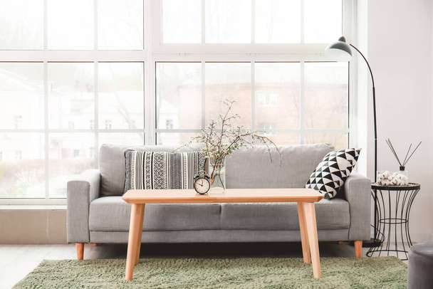 Интерьер современного номера с удобным диваном, столом и весенними цветами
 - Фото, изображение
