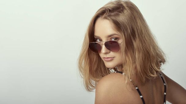 young girl in glasses, beautiful and healthy skin, natural blond hair, empty background, delicate makeup - Foto, afbeelding