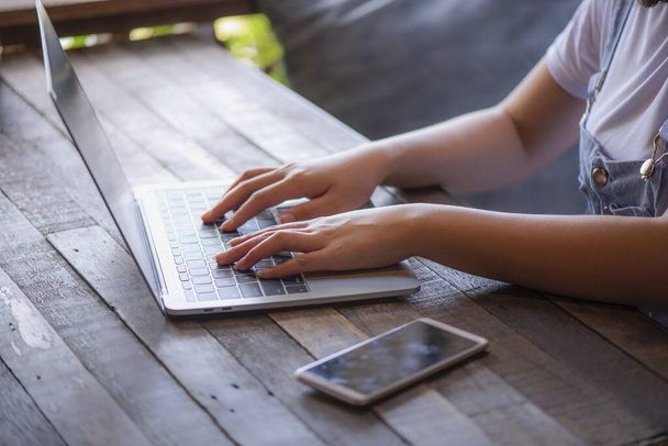 Młoda kobieta pracuje na laptopie siedząc na drewnianej podłodze - Zdjęcie, obraz