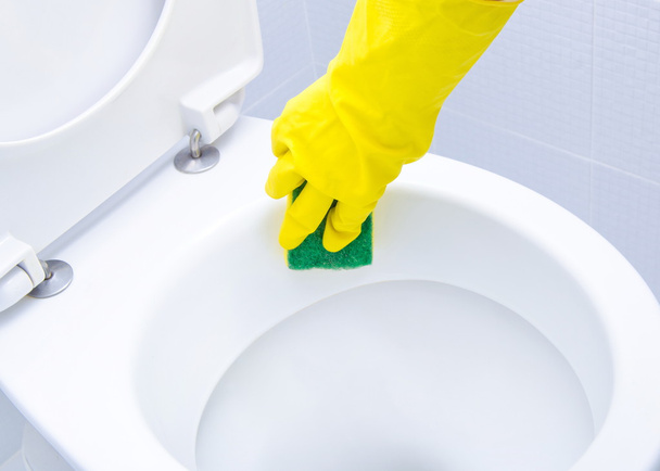 Mani su guanti gialli che puliscono un WC
 - Foto, immagini