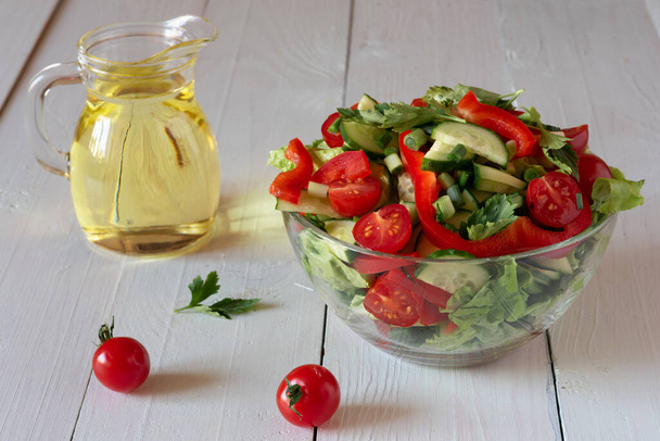 Salát na bílém dřevěném pozadí z rajčat, okurek, salátu a červeného pepře. Zdravý stravovací koncept. - Fotografie, Obrázek
