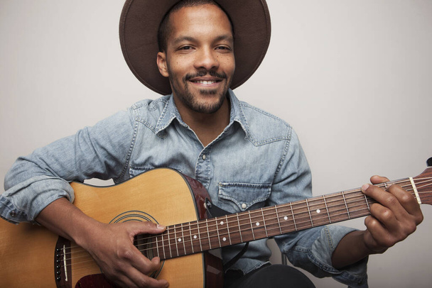 Portrait of happy bearded black man playing guitar isolated on white background. - Фото, изображение