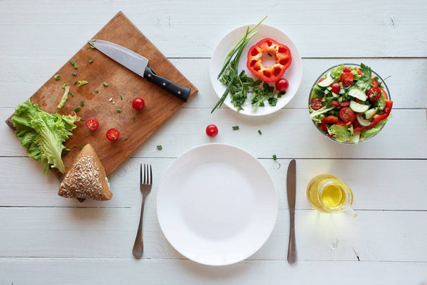 El proceso de hacer ensalada en casa sobre un fondo blanco. Vegetarianismo. Estilo de vida saludable
. - Foto, imagen