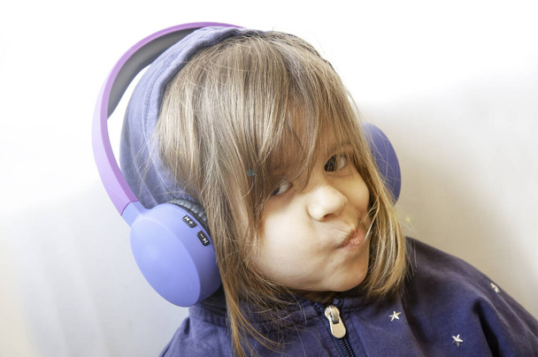 Little girl in casual sweatshirt listen music sound with pleasure grimace on her beautiful young face. Rebel and cool girl. Wireless headphones. Modern technologies, lifestyle, leisure concept. - Фото, изображение