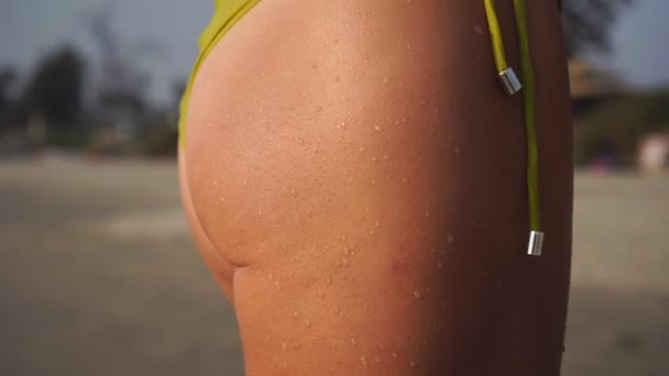 Seksowna opalona kobieta w bikini na plaży. Ciało opalonej dziewczyny w kostiumie kąpielowym - Materiał filmowy, wideo