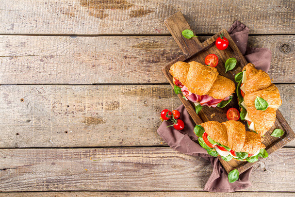 Sandwiches caseros de croissant con jamón, queso, verduras frescas y hierbas
,  - Foto, imagen