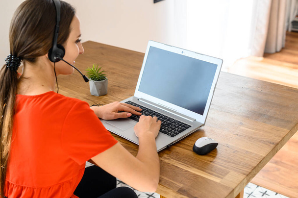 Woman works from home using headset and laptop - Valokuva, kuva