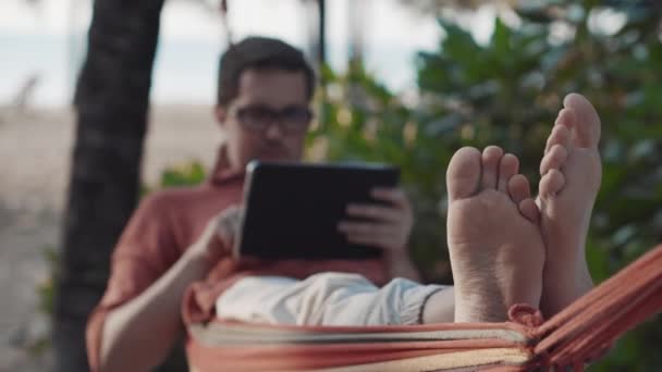 Pihenés tabletta függőágyban a strandon - Felvétel, videó