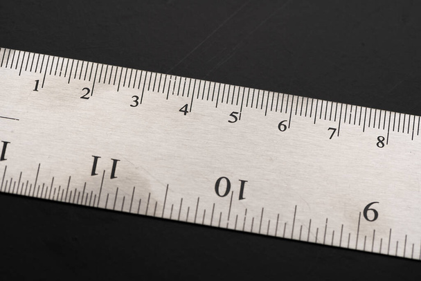 Metal ruler on a black leather isolated background with black numbers and scale. Show scale in black digit. - Photo, Image