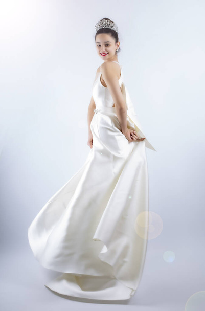 Portrait of a beautiful girl in a wedding dress. Dancing Bride, gray background. Isolated - Zdjęcie, obraz