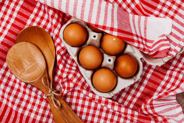 Деревянные ковши, чеснок и яйца на красно-белом ковре стола
 - Фото, изображение