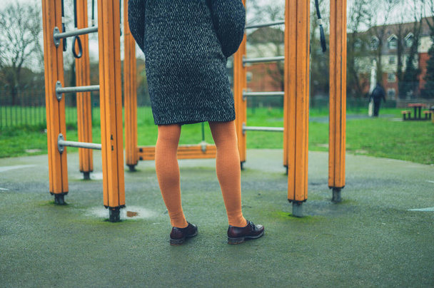 A young woman is standing by a jungle gym in the park - Foto, Imagen