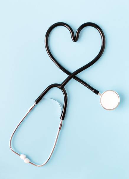 Stethoscoop vormt een hart op pastelblauwe achtergrond. Begrip "geneeskunde en gezondheid". - Foto, afbeelding