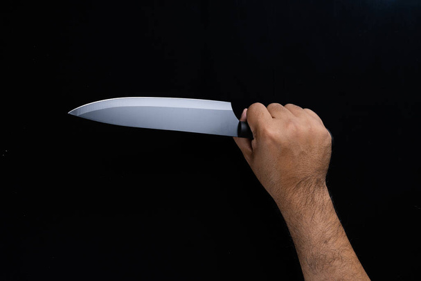 A man hand holding black chef knife isolated on Black background. - Valokuva, kuva