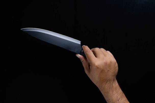 A man hand holding black chef knife isolated on Black background. - Valokuva, kuva
