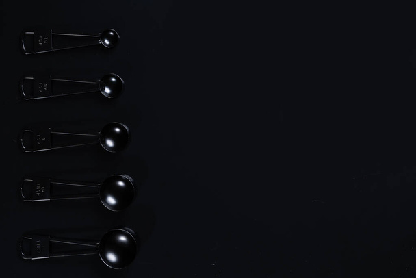 Fekete mérőkanál fekete háttér. - Fotó, kép