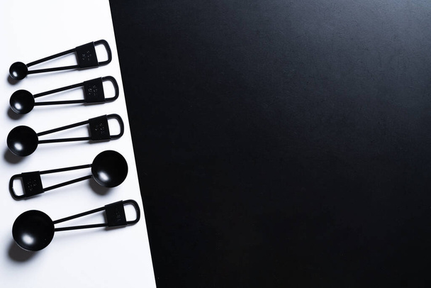 Black measuring spoons on black and white background. - Foto, Bild