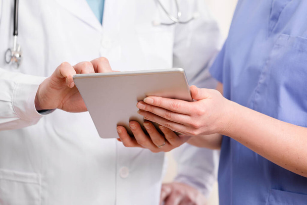 Doctor and nurse discussing patients tests at tablet computer in hospital - Photo, Image