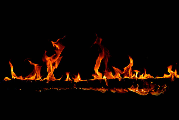 In brand vlammen op de zwarte achtergrond, gloeiende rode vonken ontstaan, felle oranje gloeiende vliegende deeltjes - Foto, afbeelding