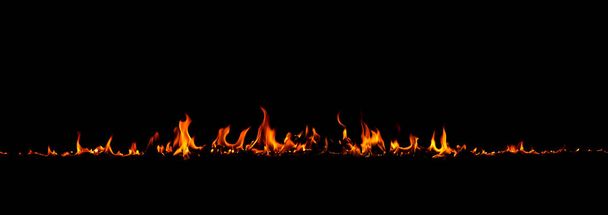 V plamenech na černém pozadí, hořící červené horké jiskry stoupají, ohnivé oranžové zářící létající částice - Fotografie, Obrázek