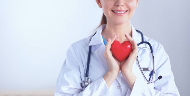 Young woman doctor holding a red heart, isolated on white background - Foto, Imagen