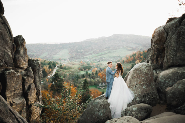 Beautiful gorgeous bride posing to groom and having fun near at mountains with amazing view, space for text, wedding couple - Fotó, kép