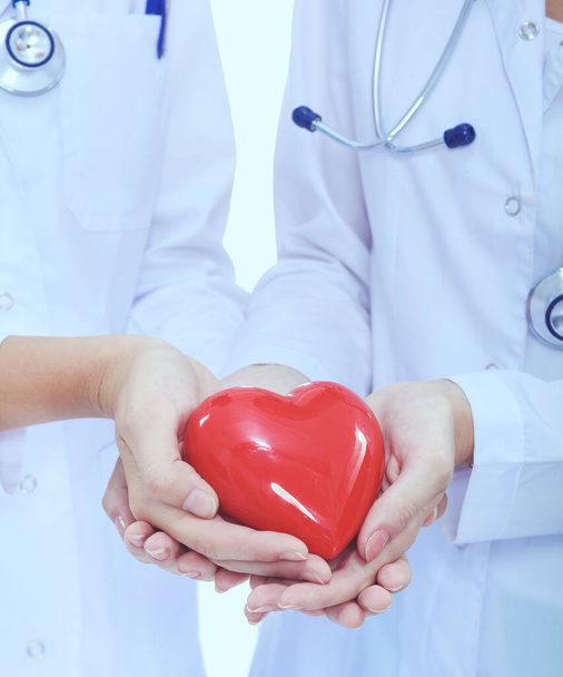白い背景に隔離された赤い心臓を持つ2人の女性医師 - 写真・画像