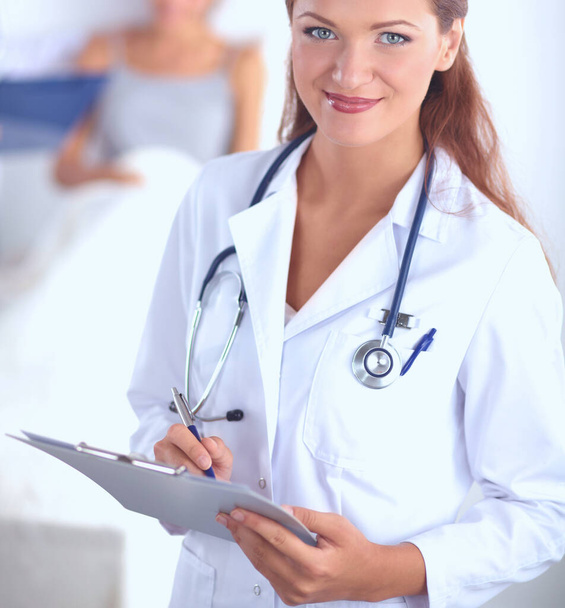 Médica sorridente com uma pasta em uniforme de pé no hospital - Foto, Imagem