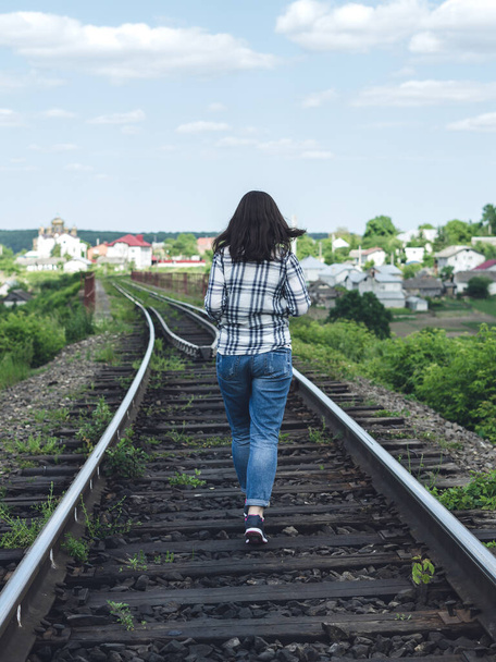 Jeune femme en jeans et chemise court le long de la voie ferrée par une journée ensoleillée
 - Photo, image