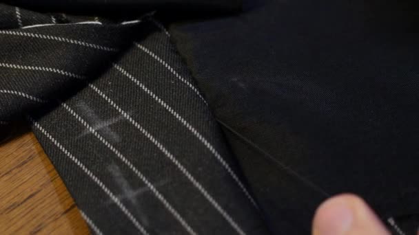 Close up tiro de ventilação de costura de alfaiate profissional com agulha e linha. listrado tecido terno de lã preta
 - Filmagem, Vídeo