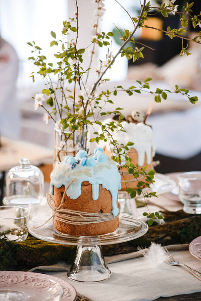 mesa decorada para a Páscoa: bolos de Páscoa, ovos de Páscoa, coelhos de Páscoa, ramos de cereja floridos em copos de vidro, pratos e copos
 - Foto, Imagem