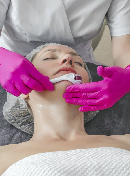 Retrato de close-up da mulher que processa a pele no salão de beleza. Médico prepara a pele usando um mesoscooter. - Foto, Imagem