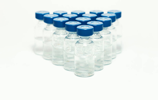 Glass medicine bottles with vaccine injection fluid with blue aluminium caps for vaccination, Coronavirus Covid-19 concept - Fotó, kép